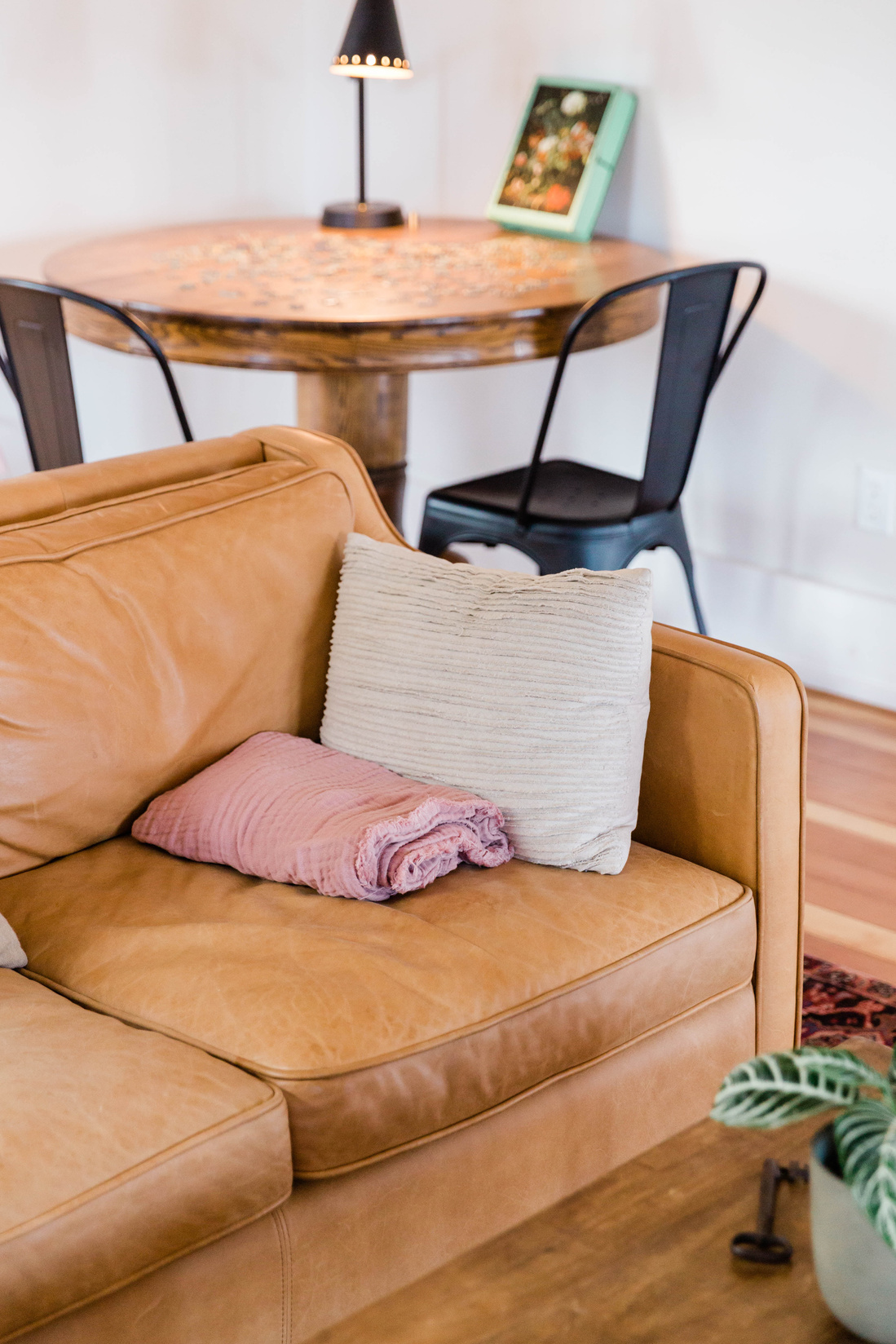 a leather couch in a living room with pillows and a potted plant