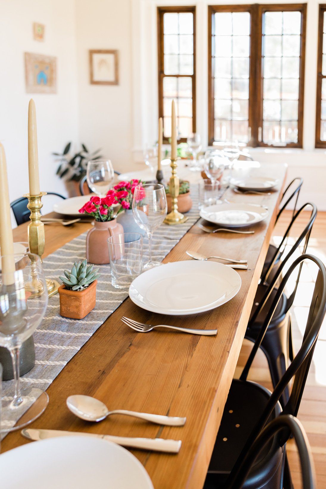 a long wooden table is set with plates, silverware and utensils